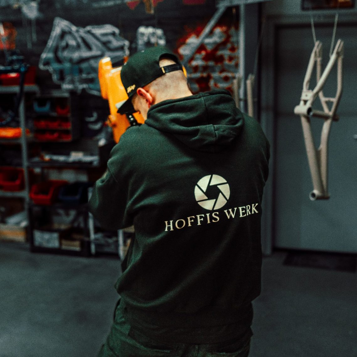 Daniel mit Kapuzenpulli mit Logo beim Fotografieren in einem Firmenlager